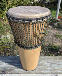 Stave shell ashiko with goat skin drum head for sale.